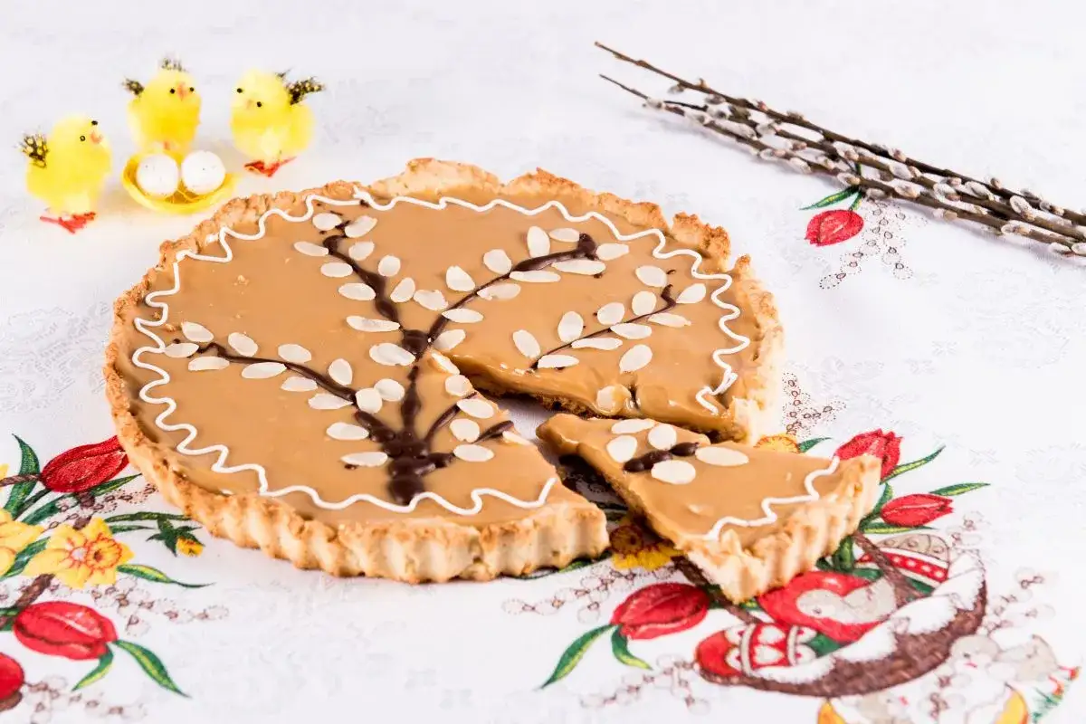 Pyszny mazurek wielkanocny przepis na słodki deser z migdałami i czekoladowym drzewkiem. Dekoracja z kurczaczkami i baziami.
