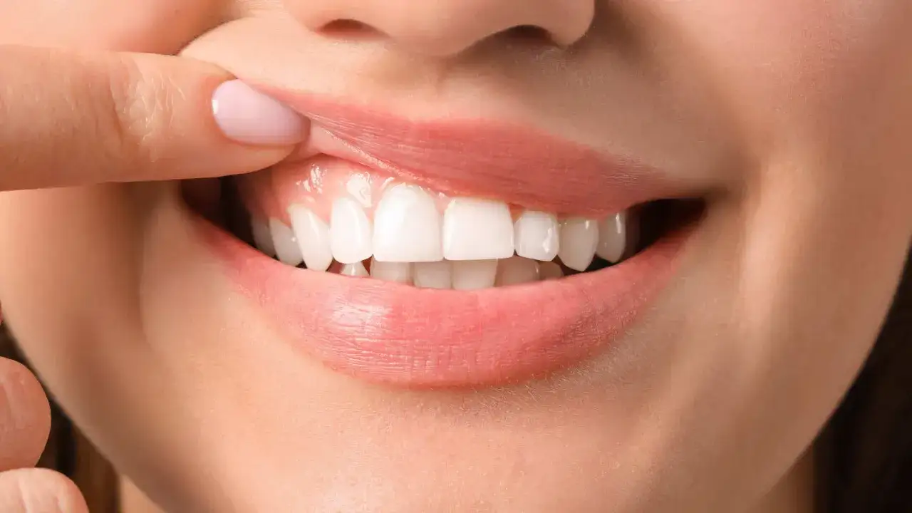 Dłoń odsłaniająca zdrowe, białe zęby i różowe dziąsła. To właśnie oznacza gum care – troska o piękny uśmiech.