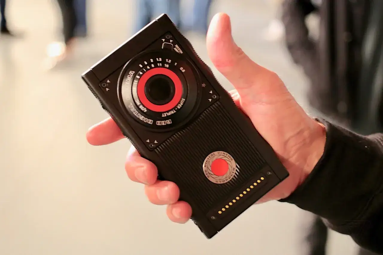 Dłoń trzyma czarny telefon RED Hydrogen One z czerwonym akcentem.