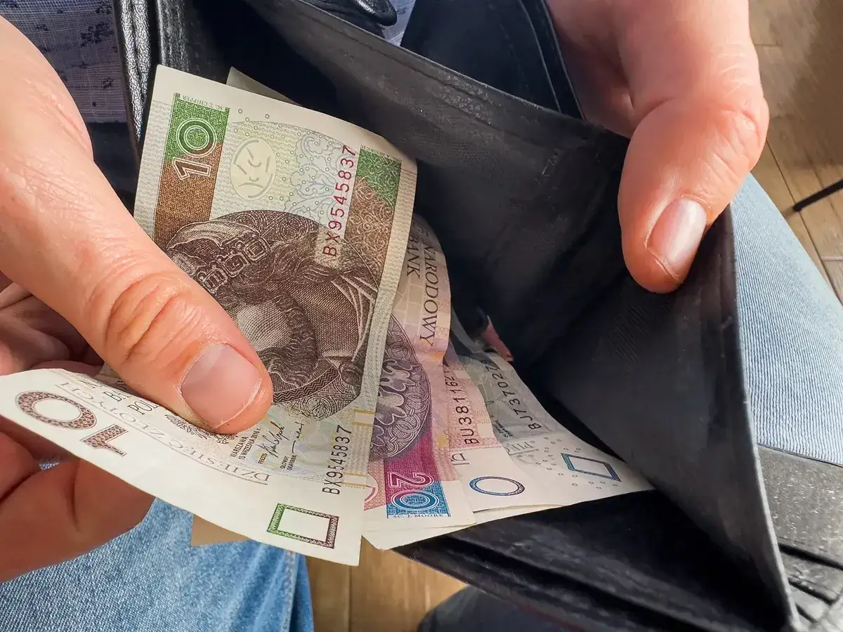 Dłoń wyciąga polskie banknoty z portfela. Zastanawiasz się, czy mieszkaniówka wlicza się do dochodu?