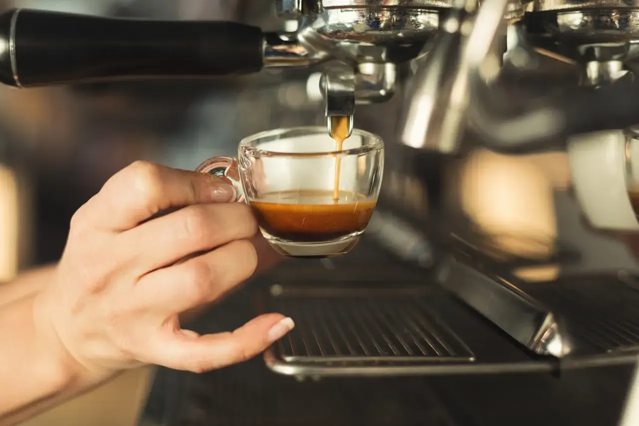 Ręce przygotowujące espresso macchiato, kroki parzenia