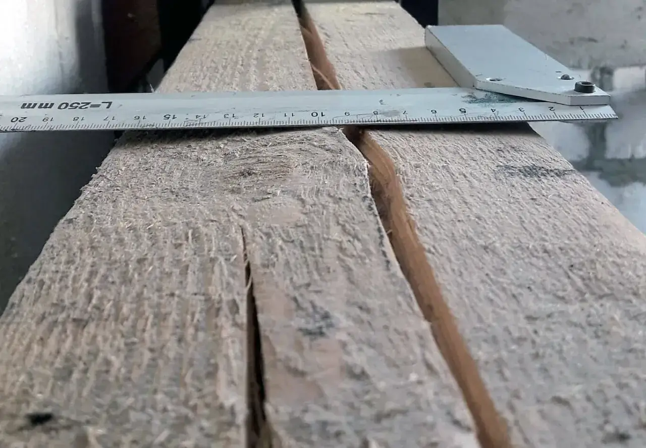 Drewno pęka, a miarka pokazuje głębokość szczeliny. Dowiedz się, jak zabezpieczyć pękające drewno przed dalszym niszczeniem.