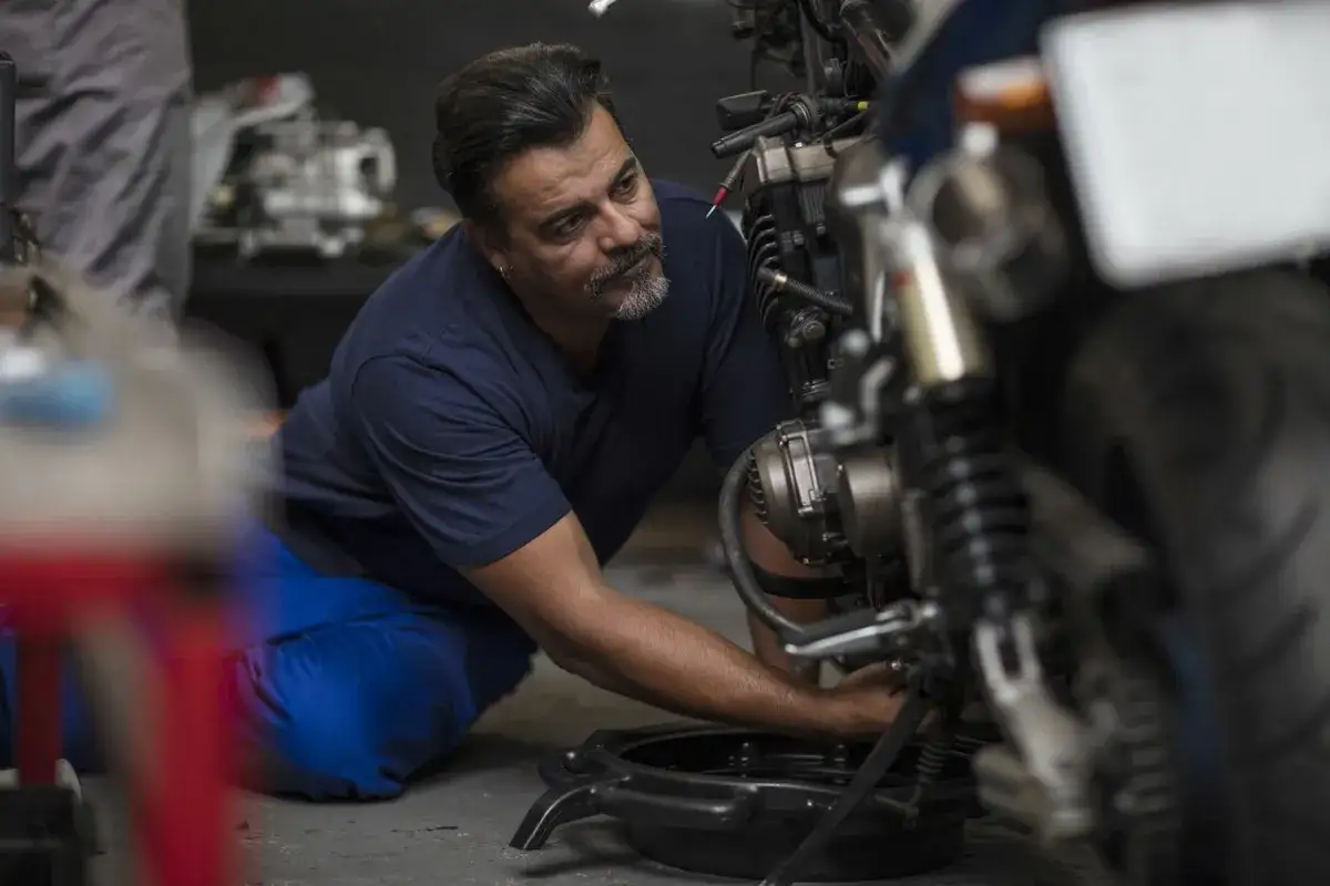 Mechanik wymienia olej w motocyklu. Pamiętaj o regularnej wymianie oleju co ile km wymiana oleju w motocyklu, by zapewnić jego długą żywotność.