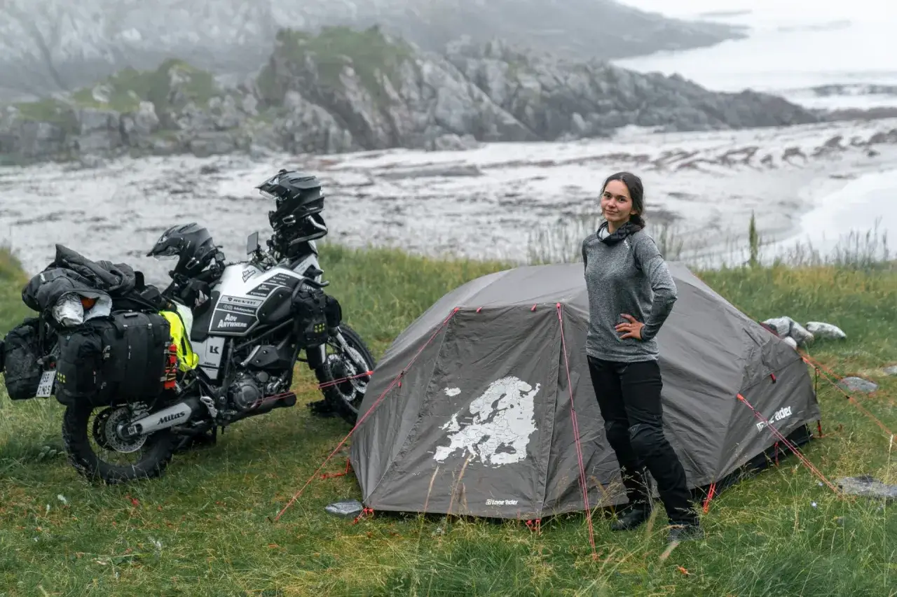 Kobieta obok namiotu z mapą Europy i motocyklem przygotowanym do podr&oacute;ży. Idealny namiot na motocykl na wyprawę.