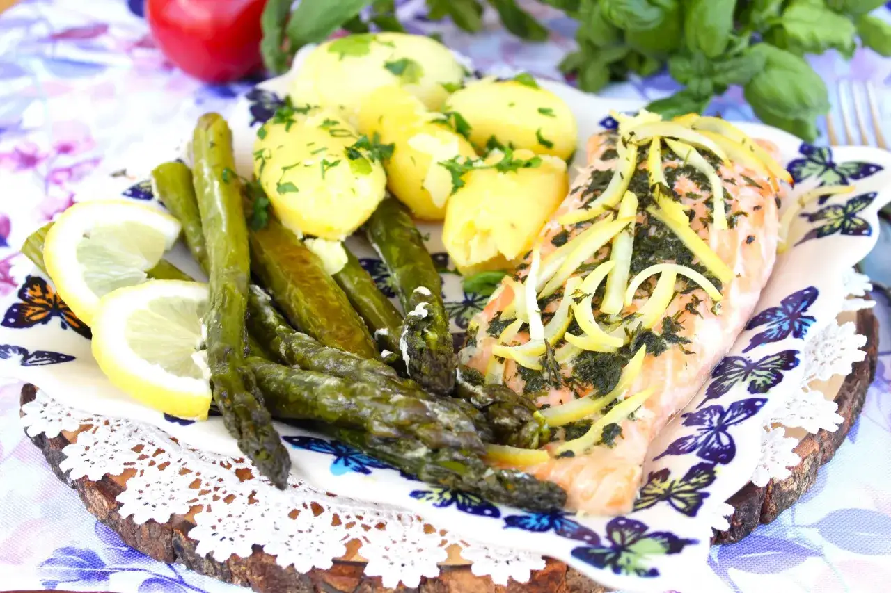 Pyszny łosoś ze szparagami, ziemniakami i cytryną, udekorowany ziołami. Idealny posiłek na letni dzień.