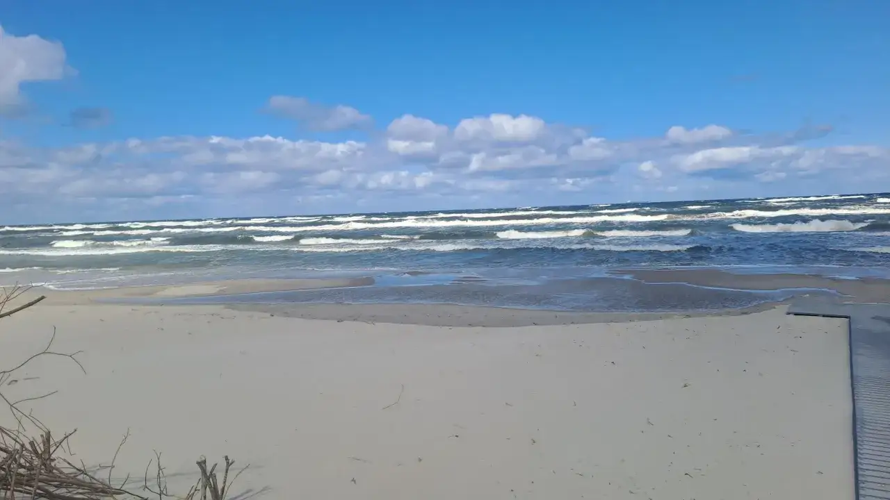 Piękny dzień, kiedy jod nad morzem w pełni. Falujące morze, piaszczysta plaża i błękitne niebo z chmurami.