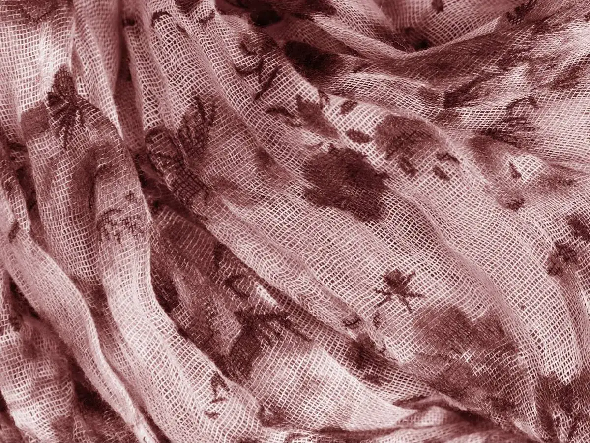 Delikatny, zwiewny materiał modal w kolorze pudrowego różu z ciemniejszym, kwiatowym wzorem. Widać jego lekką, ażurową strukturę.