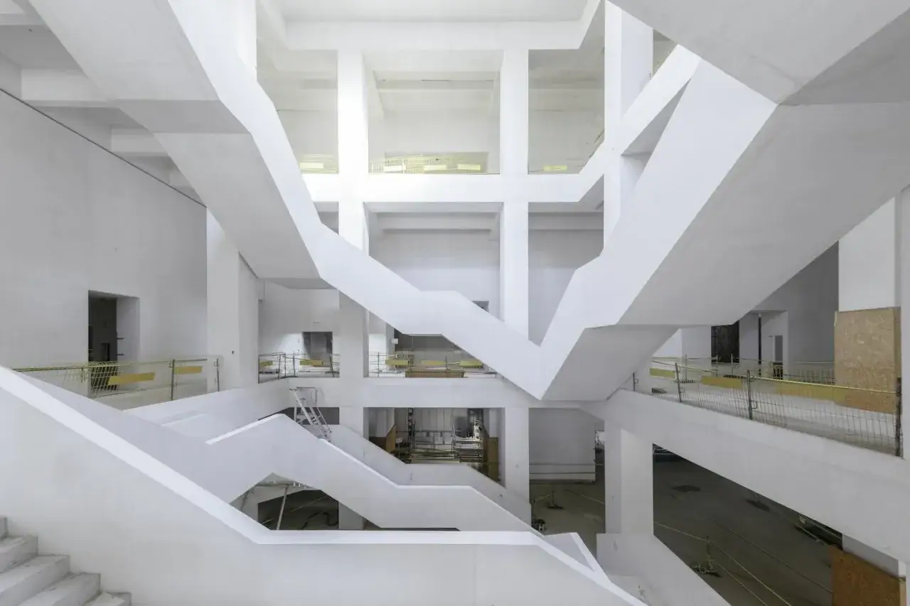 Wnętrze muzeum sztuki nowoczesnej Warszawa projekt: białe, geometryczne schody i belki tworzą labirynt.