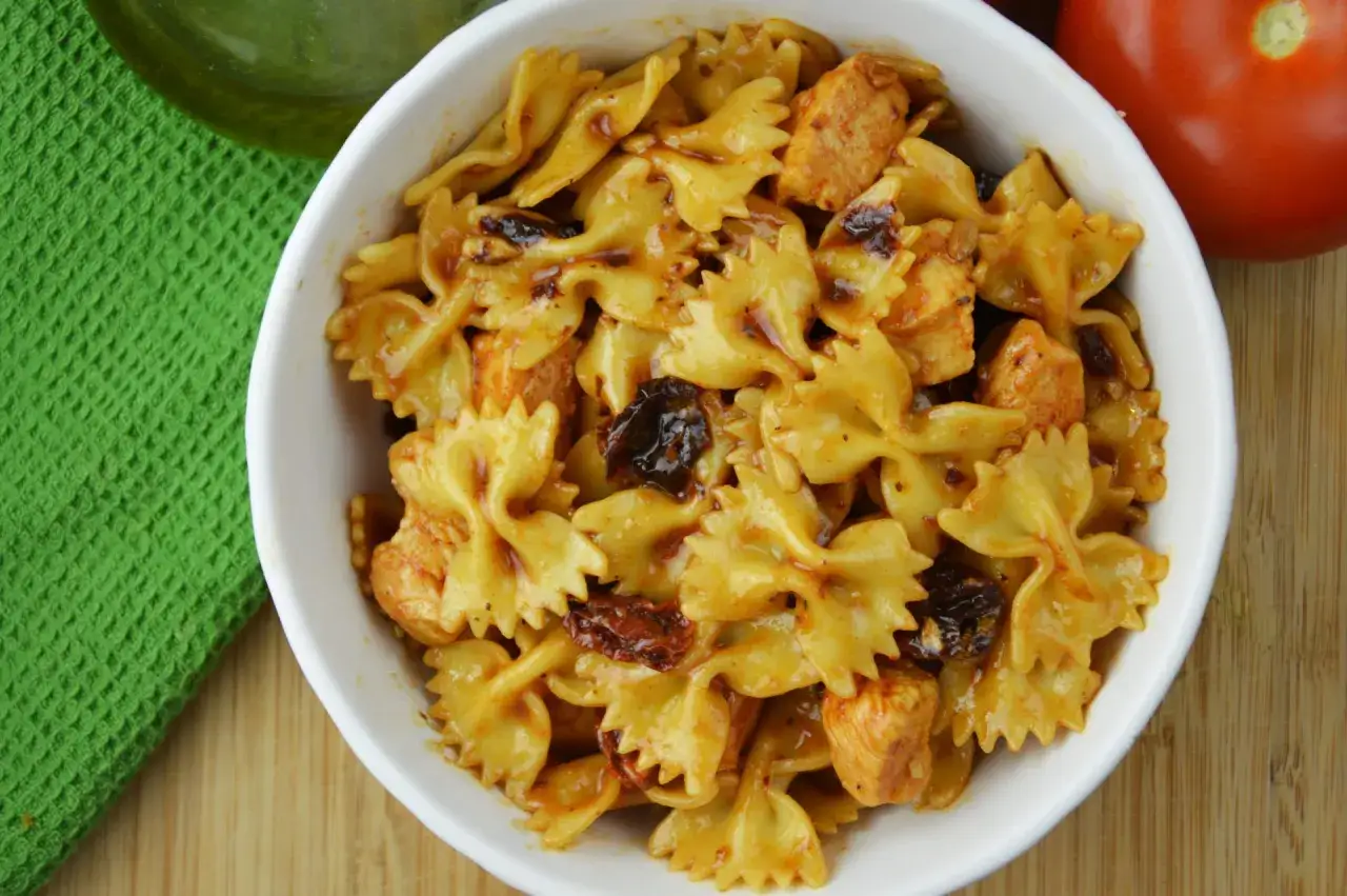 Pyszna sałatka z makaronem kokardki, kawałkami kurczaka i suszonymi pomidorami w sosie.