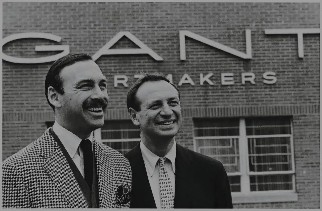 Dw&oacute;ch mężczyzn uśmiecha się przed budynkiem z napisem GANT. To pytanie 