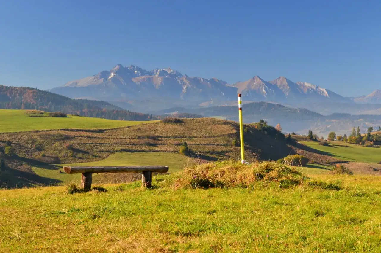 Ławka i słup znakujący szlak na lesnicke sedlo. W tle majestatyczne g&oacute;ry.