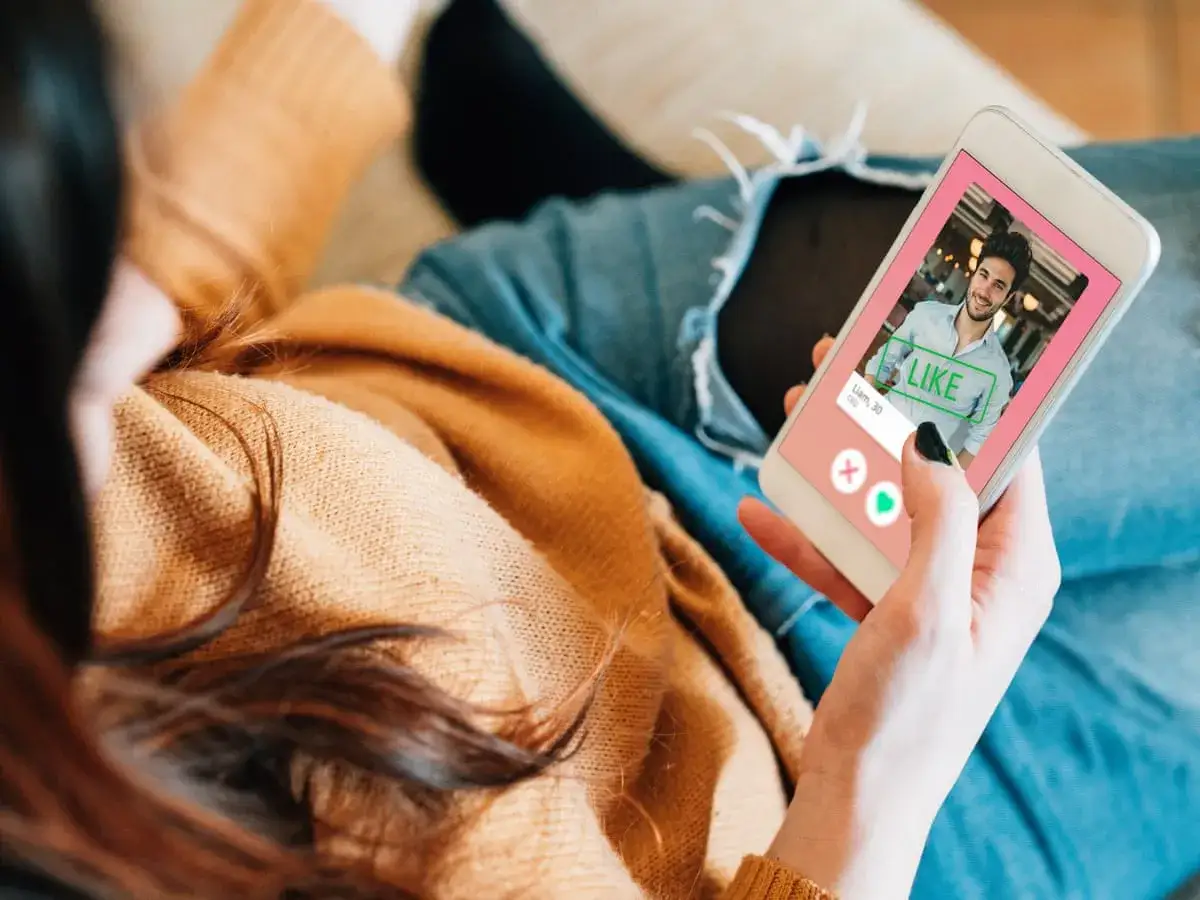 Kobieta przegląda profile na Tinderze, szukając idealnego dopasowania. Widzi zdjęcie uśmiechniętego mężczyzny z napisem 