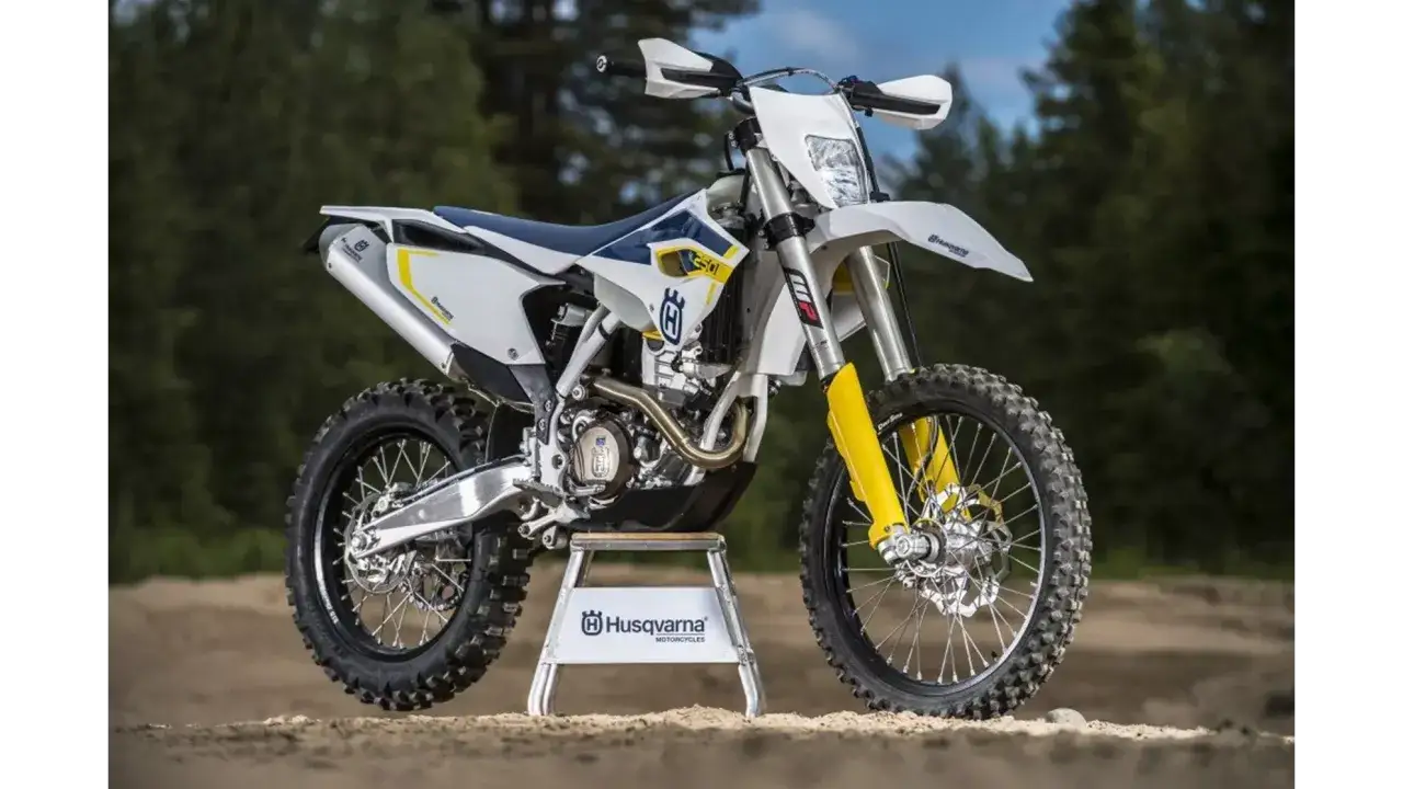 Potężny motocykl Husqvarna 250 FE gotowy na terenowe wyzwania. Biało-niebieska maszyna z ż&oacute;łtymi akcentami prezentuje się imponująco.