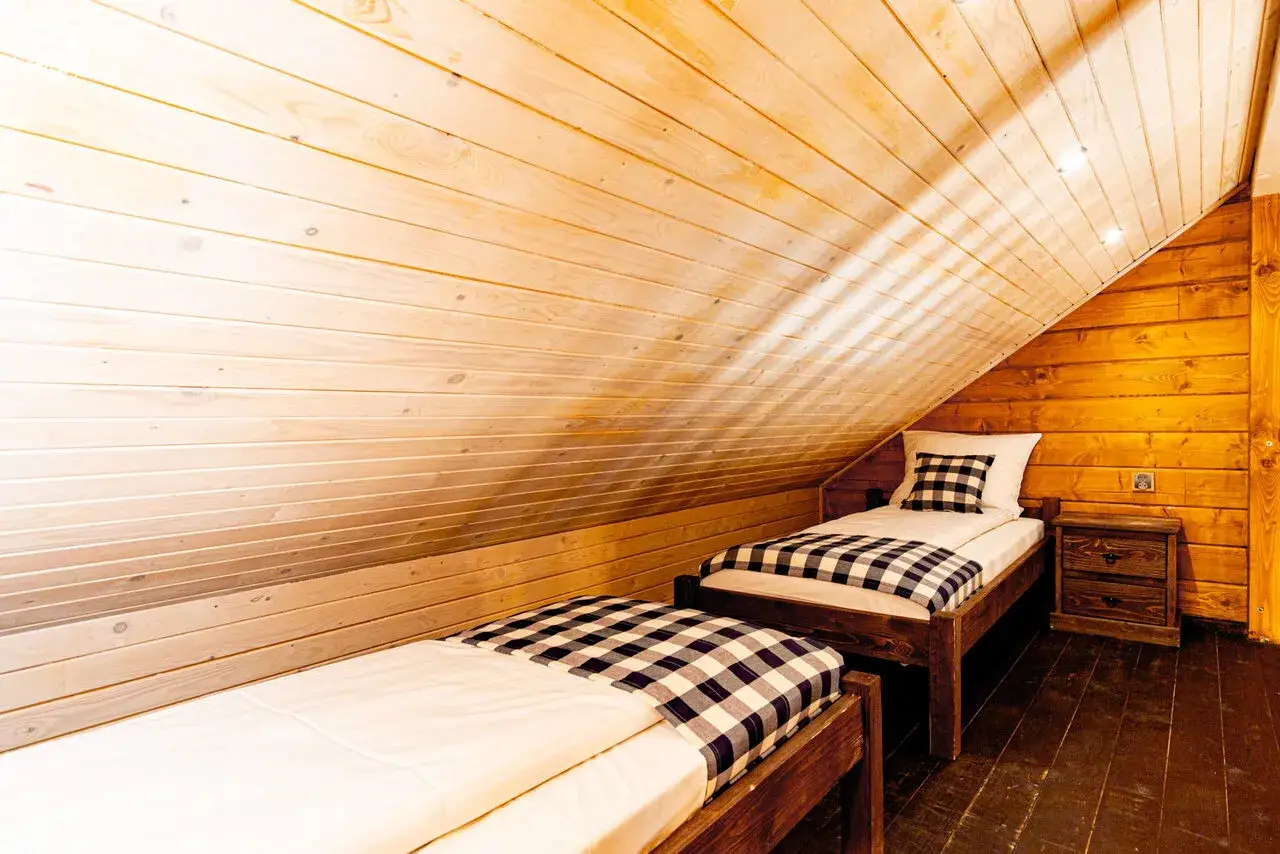 Drewniana sypialnia z dwoma łóżkami w kratę. Zastanawiasz się, ile kosztuje nocleg w Energylandii?