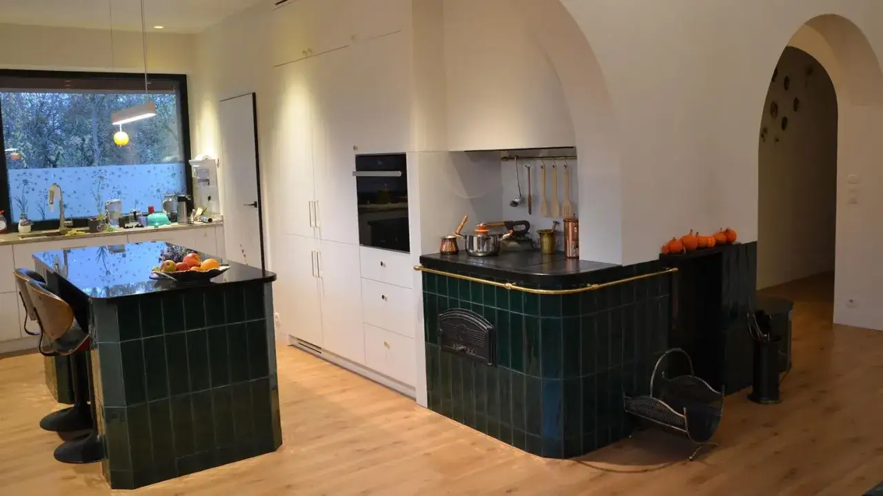 Nowoczesna kuchnia z wyspą i piecem kaflowym. Zobacz, jak zrobić kuchnię kaflową w tym stylu.