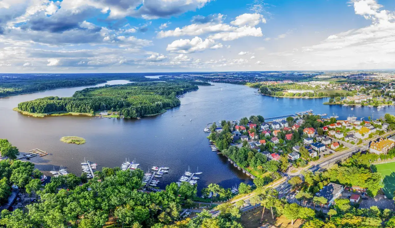 Widok z lotu ptaka na jezioro z wyspą, lasami i zabudowaniami. Ile jest wysp w Polsce? Tyle, ile pięknych widoków jak ten!