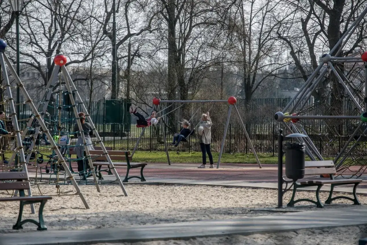 Dzieci bawią się na placu zabaw, huśtając się i wspinając. Kiedy zostaną otwarte **zamknięte place zabaw do kiedy**?