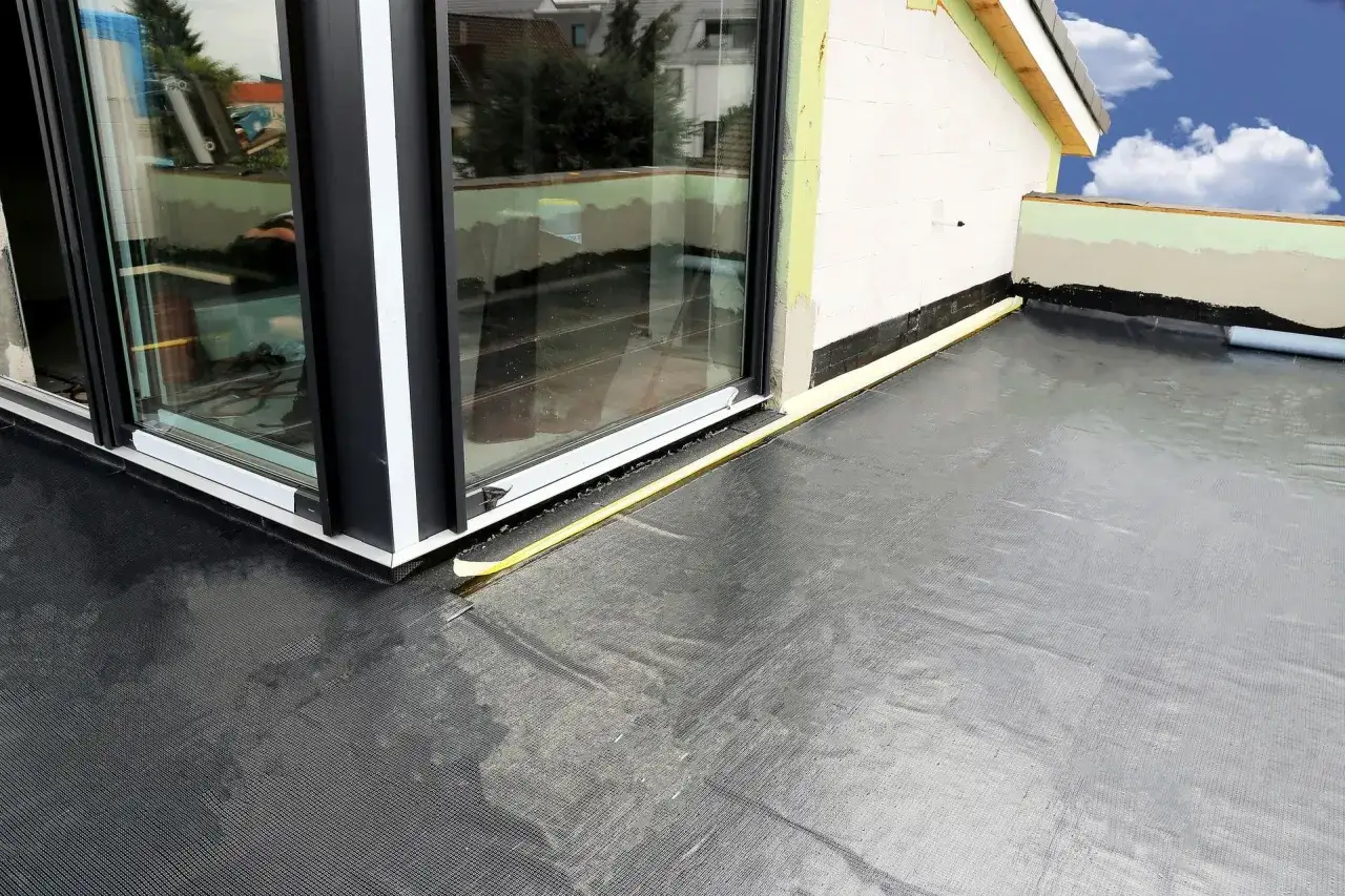 Nowy balkon w bloku z wielkiej płyty, z czarną membraną hydroizolacyjną i dużymi oknami.