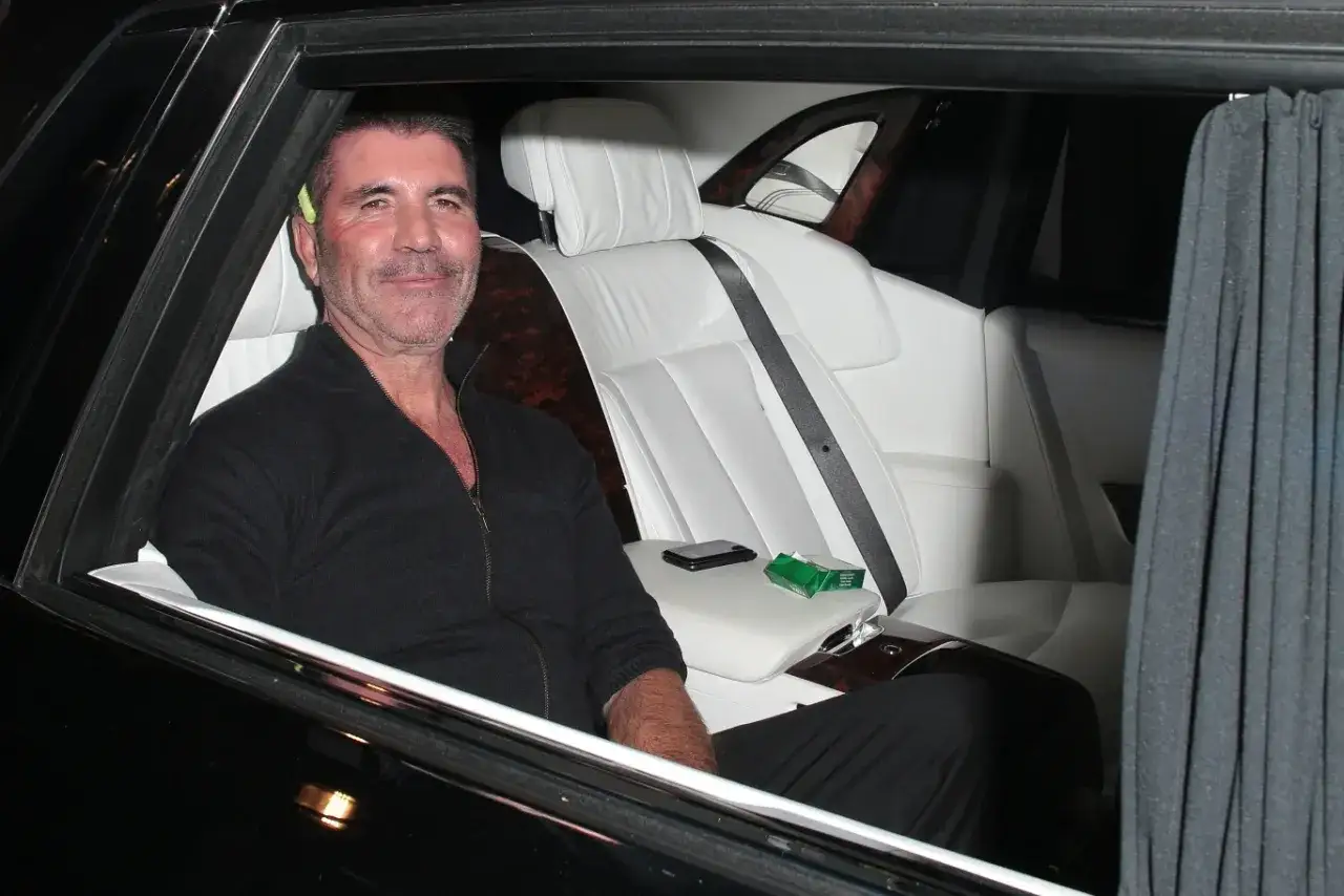 Simon Cowell w luksusowym aucie, uśmiecha się. Plotki, że Simon Cowell nie żyje, są nieprawdziwe.