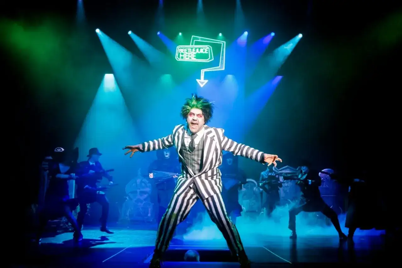 Aktor w stroju Beetlejuice na scenie. Sprawdź repertuar teatru muzycznego Warszawa, by zobaczyć ten spektakl!