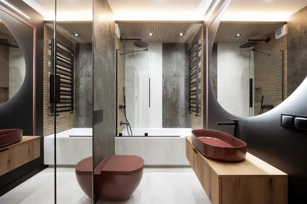 Nowoczesna łazienka z rustykalnym akcentem. Ściany zdobi tynk dekoracyjny do łazienki imitujący kamień i drewno. Ciemnoczerwona ceramika dodaje elegancji.
