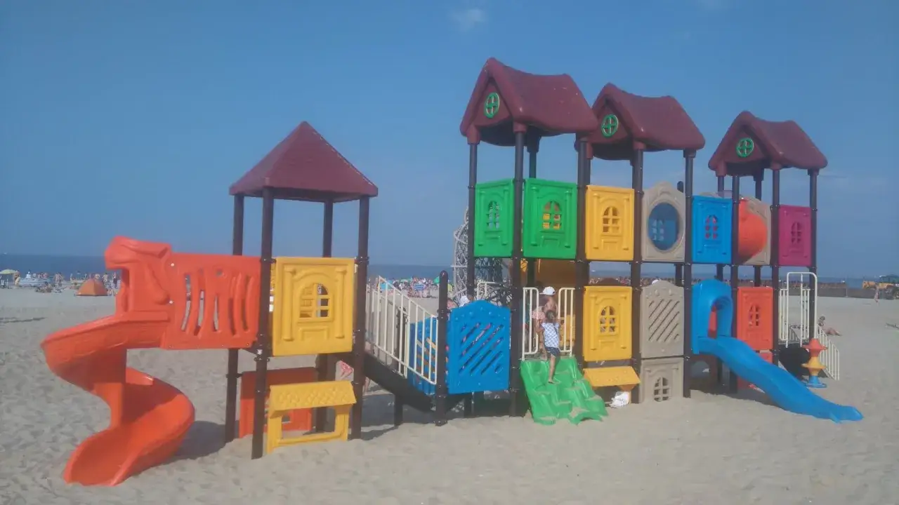 Kolorowy plac zabaw na plaży, idealne atrakcje dla dzieci nad morzem. Zjeżdżalnie i drabinki zachęcają do zabawy.