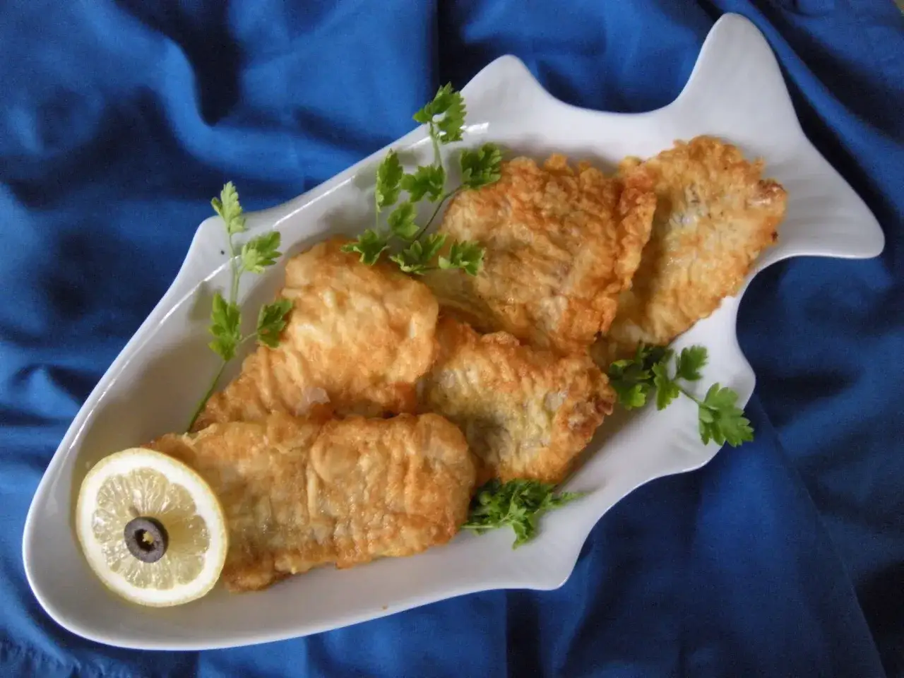 Świeży filet z mintaja na desce do krojenia z ziołami