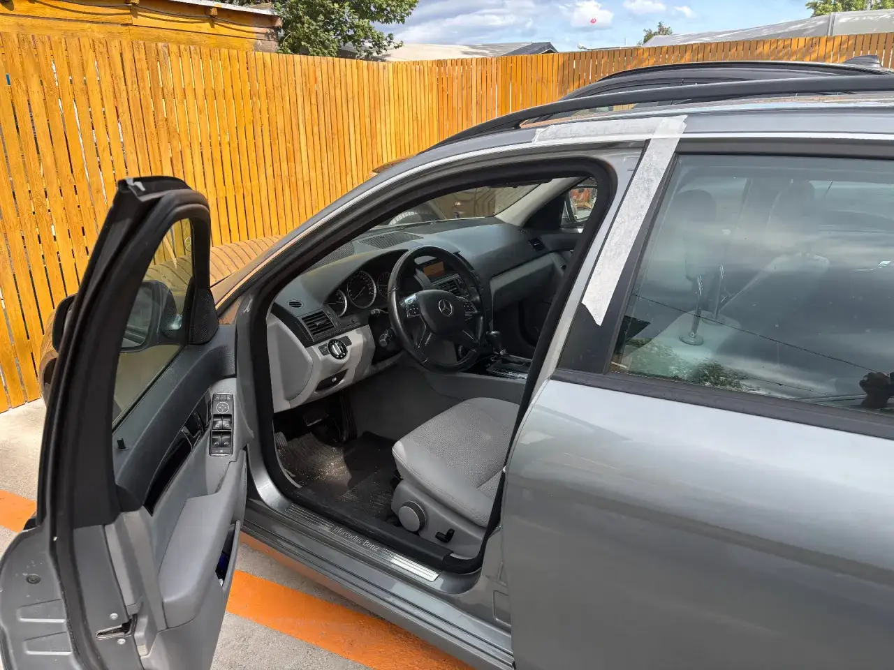 Szara stacja kombi z otwartymi drzwiami. Taśma na górnej krawędzi drzwi pasażera sugeruje, jak otworzyć samochód bez kluczyków.