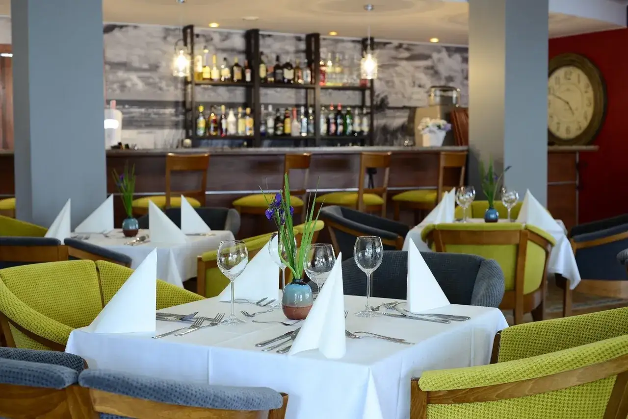 Elegancka restauracja hotelu La Siesta z nakrytymi stołami, barem i wygodnymi fotelami.