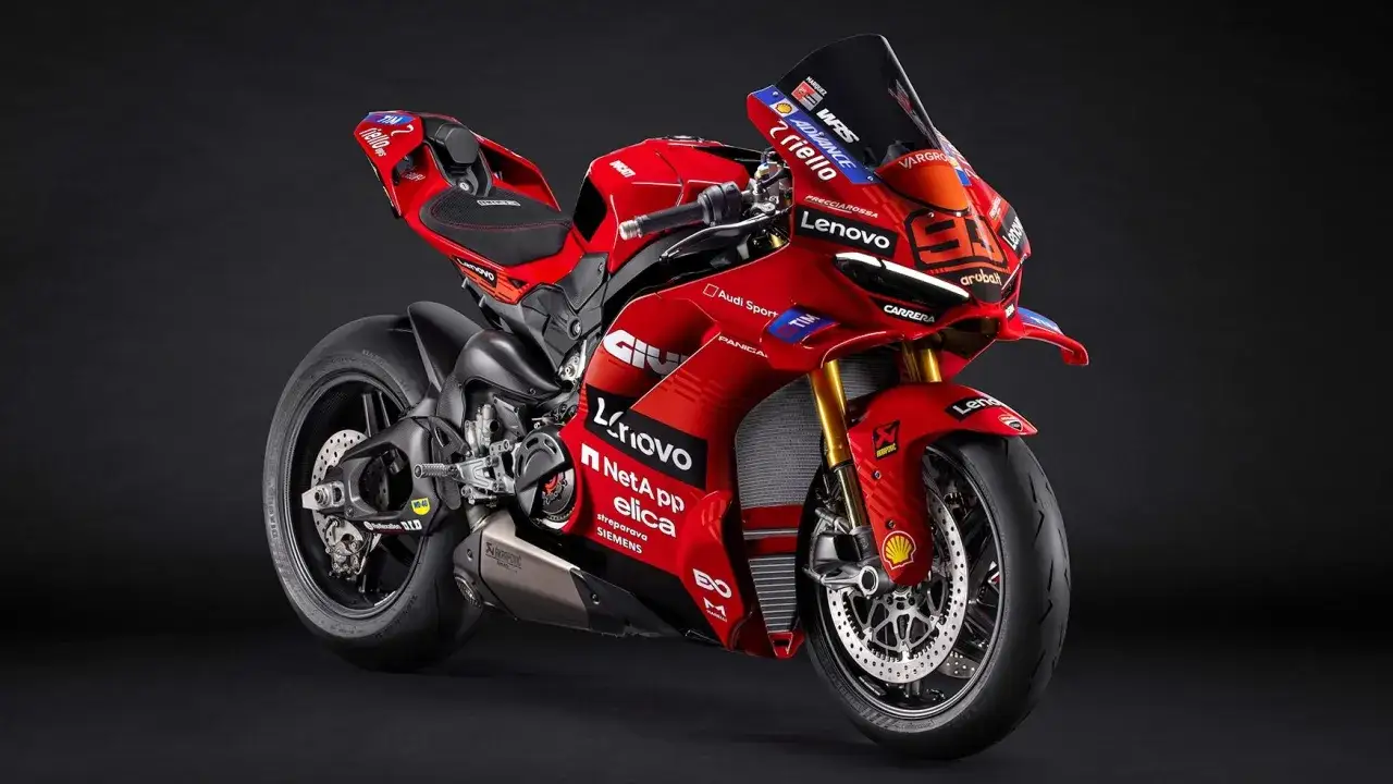 Czerwony motocykl wyścigowy Ducati Panigale V4 z licznymi sponsorami, gotowy do startu.