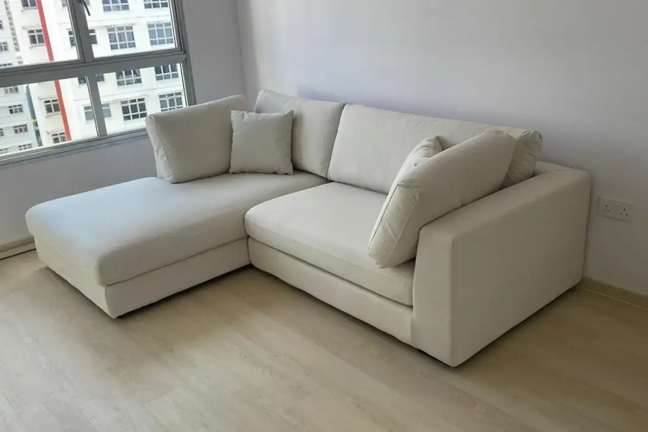 Jasnoszara, narożna sofa z poduszkami. Idealna do salonu, dzięki tkaninom obiciowym łatwym do czyszczenia.
