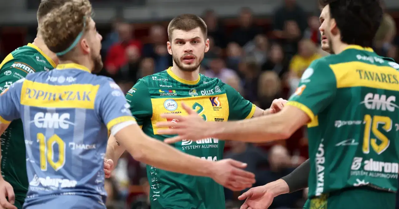 Siatkarze w zielonych strojach, grający w lidze mistrzów siatkówka, wymieniają uściski dłoni.