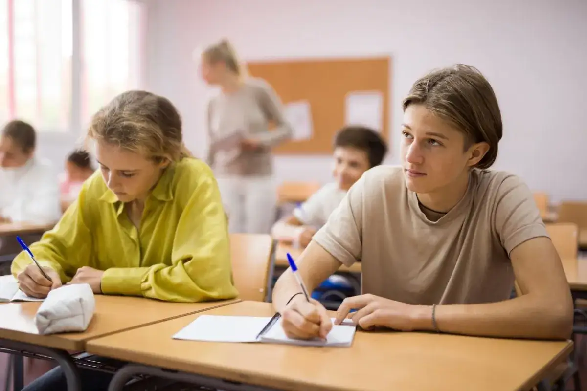 Uczniowie w klasie, skupieni na lekcji. To obraz polskiego wykształcenia, gdzie młodzi ludzie zdobywają wiedzę.