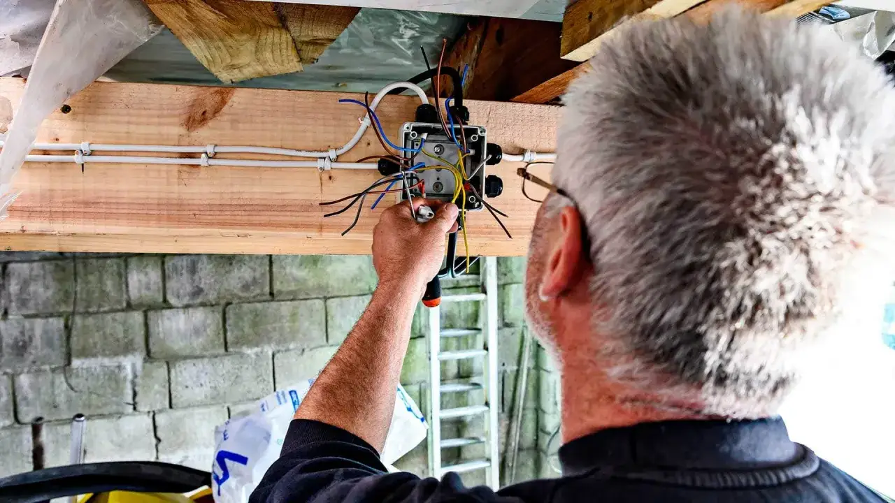 Elektryk podłącza przewody do puszki, przygotowując instalację pod oświetlenie LED 230V.