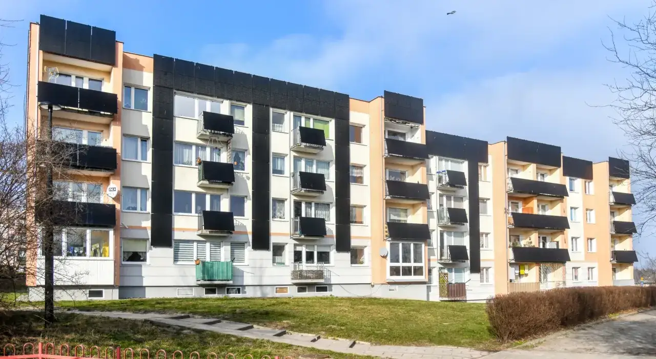 Blok mieszkalny z panelami fotowoltaicznymi na balkonach. Ekologiczne rozwiązania dla mieszkańców.