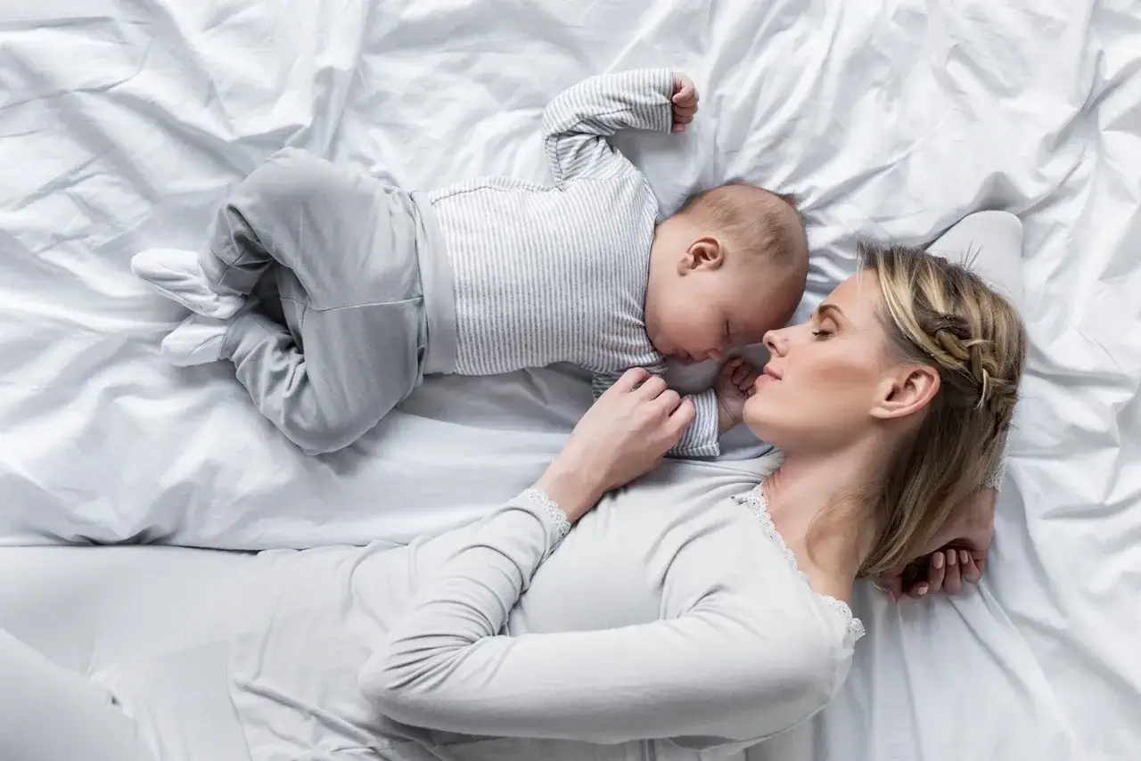 Mama i dziecko śpią razem, co rodzi pytanie: czy dziecko powinno spać z rodzicami? Bliskość i spokój.