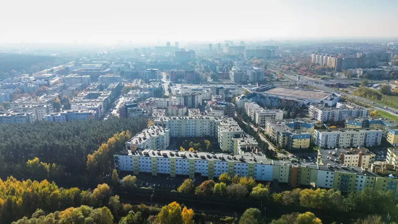 Widok z lotu ptaka na osiedle mieszkaniowe w Poznaniu. Kolorowe bloki otoczone zielenią, idealne miejsce do życia. Poznań ceny mieszkań mogą być tu atrakcyjne.