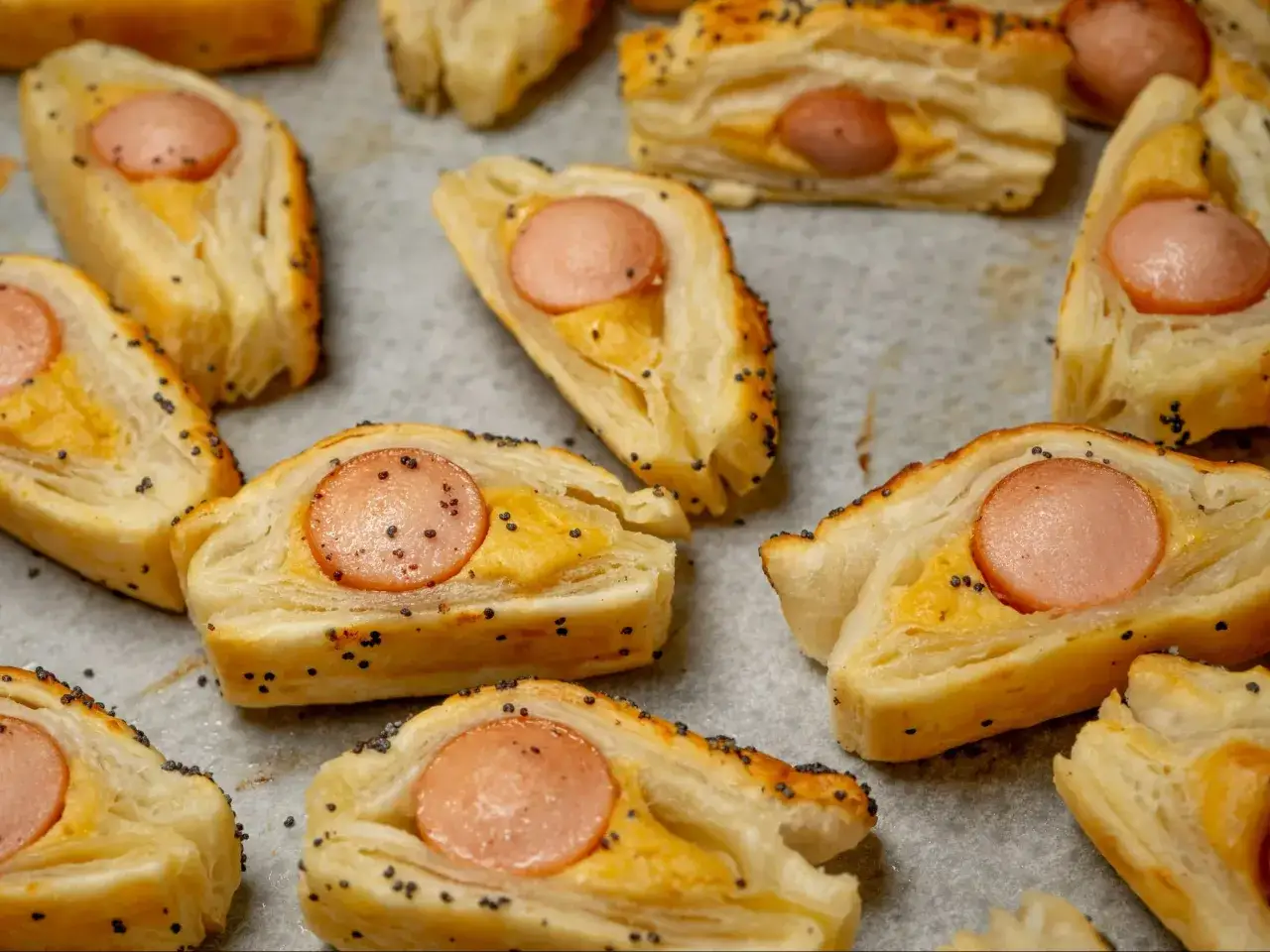 Pyszne parówki w cieście francuskim posypane makiem. Idealny pomysł na to, co można zrobić z ciasta francuskiego na szybką przekąskę.