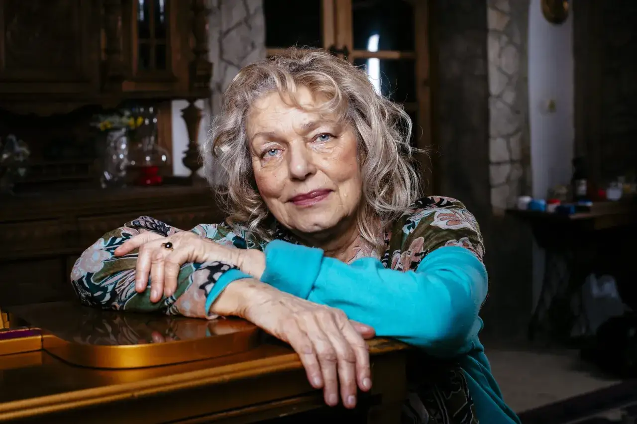 Katarzyna Gaertner, zamyślona, opiera się o fortepian. W jej oczach widać ciepło, jakby wspominała swoje dzieci.