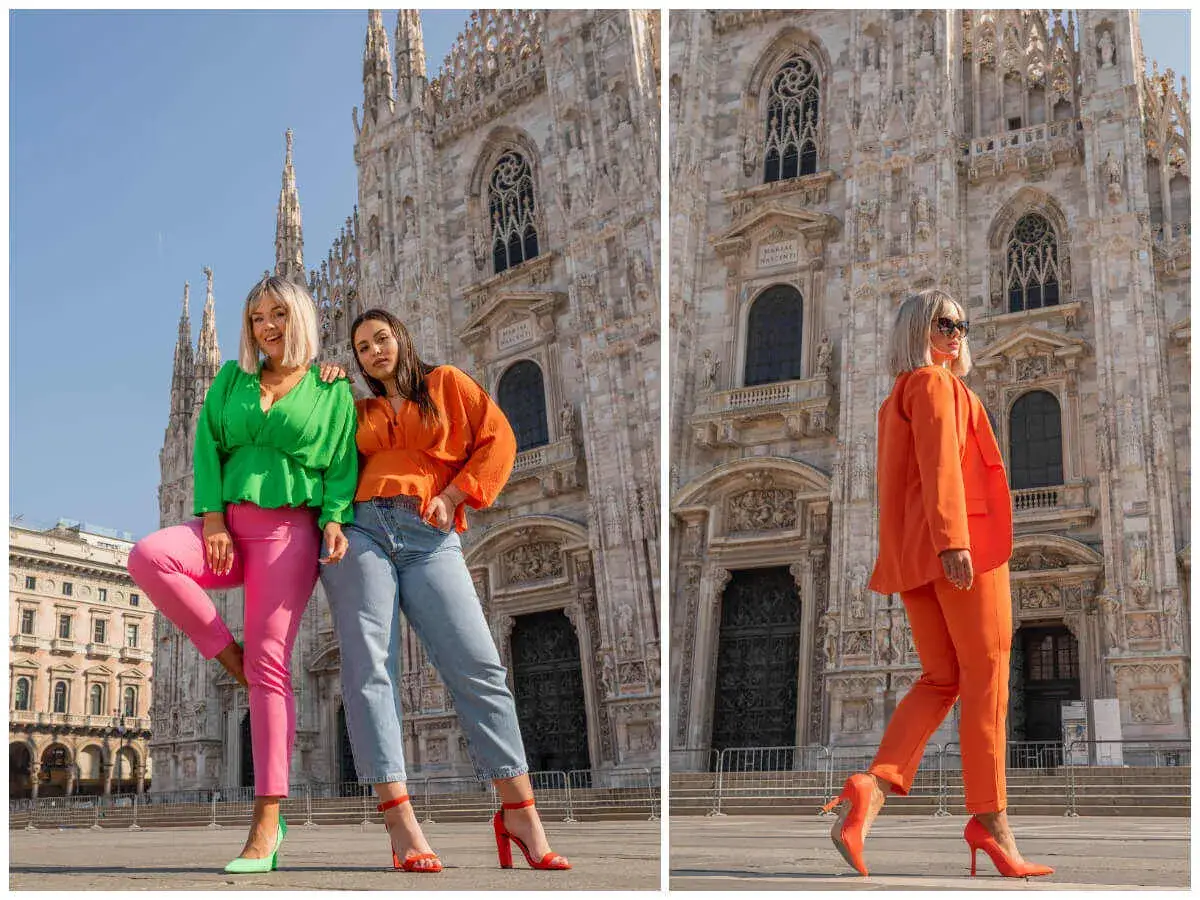 Trzy kobiety w stylizacjach pomarańczowy i zielony przed katedrą. Jedna w zielonej bluzce i różowych spodniach, druga w pomarańczowej bluzce i jeansach, trzecia w pomarańczowym garniturze.