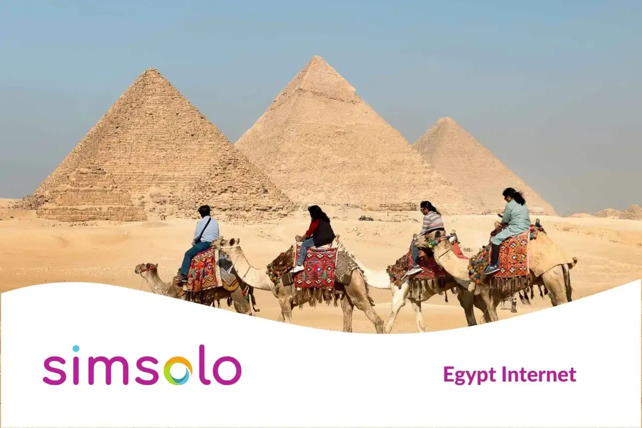 Ludzie na wielbłądach przed piramidami w Gizie. Zapewnij sobie szybki internet w Egipcie, by dzielić się wrażeniami.