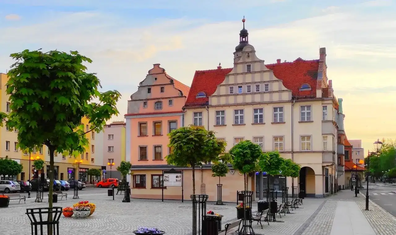 Urokliwy rynek we Lw&oacute;wku Śląskim z kolorowymi kamieniczkami i zielenią. Atrakcje miasta zachęcają do spacer&oacute;w.