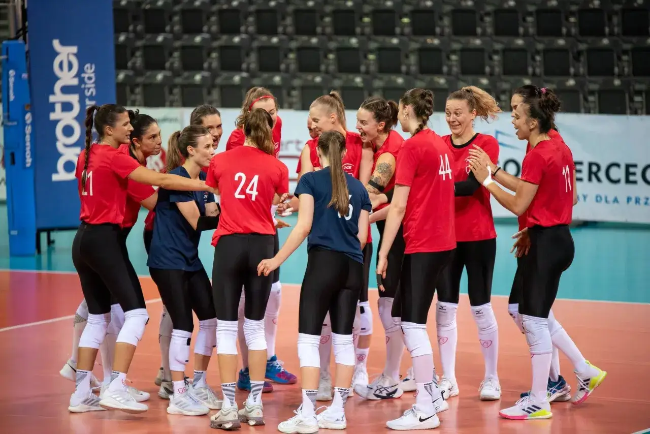 Siatkarki w czerwonych strojach tworzą zgrany **grot budowlani skład**, gotowe do walki na boisku.