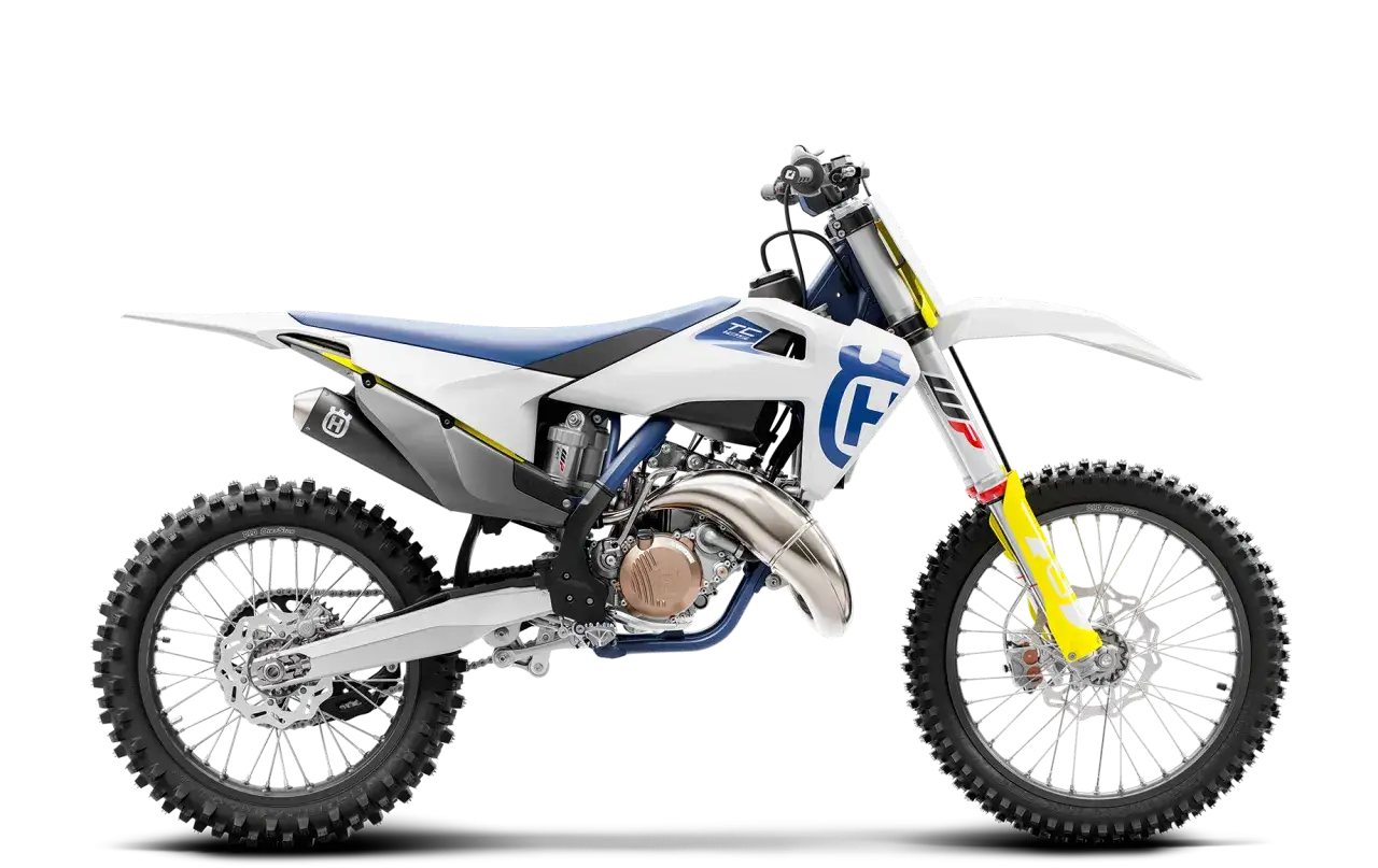Motocykl Husqvarna TC 125 w białej odsłonie z niebieskimi i ż&oacute;łtymi akcentami, gotowy do podboju toru.