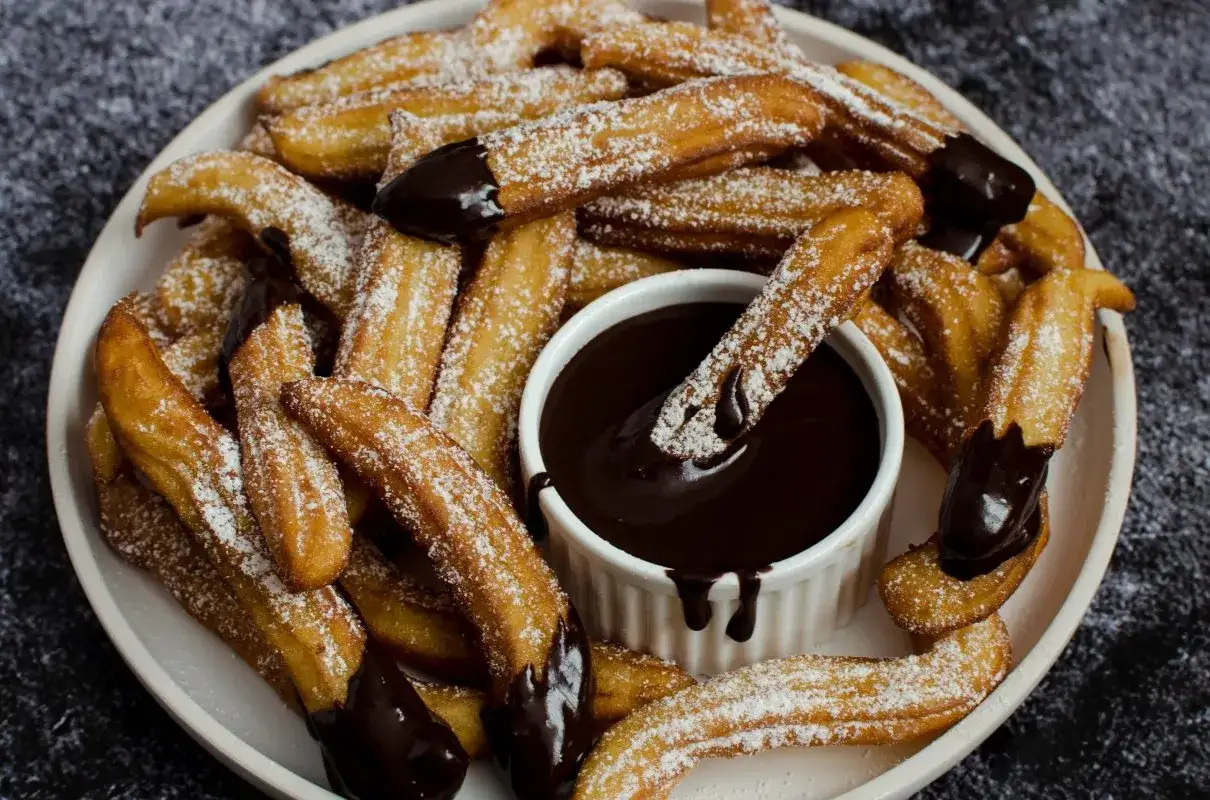 Churros przepis: złociste, posypane cukrem pudrem, zanurzane w gorącej czekoladzie. Idealne na deser!