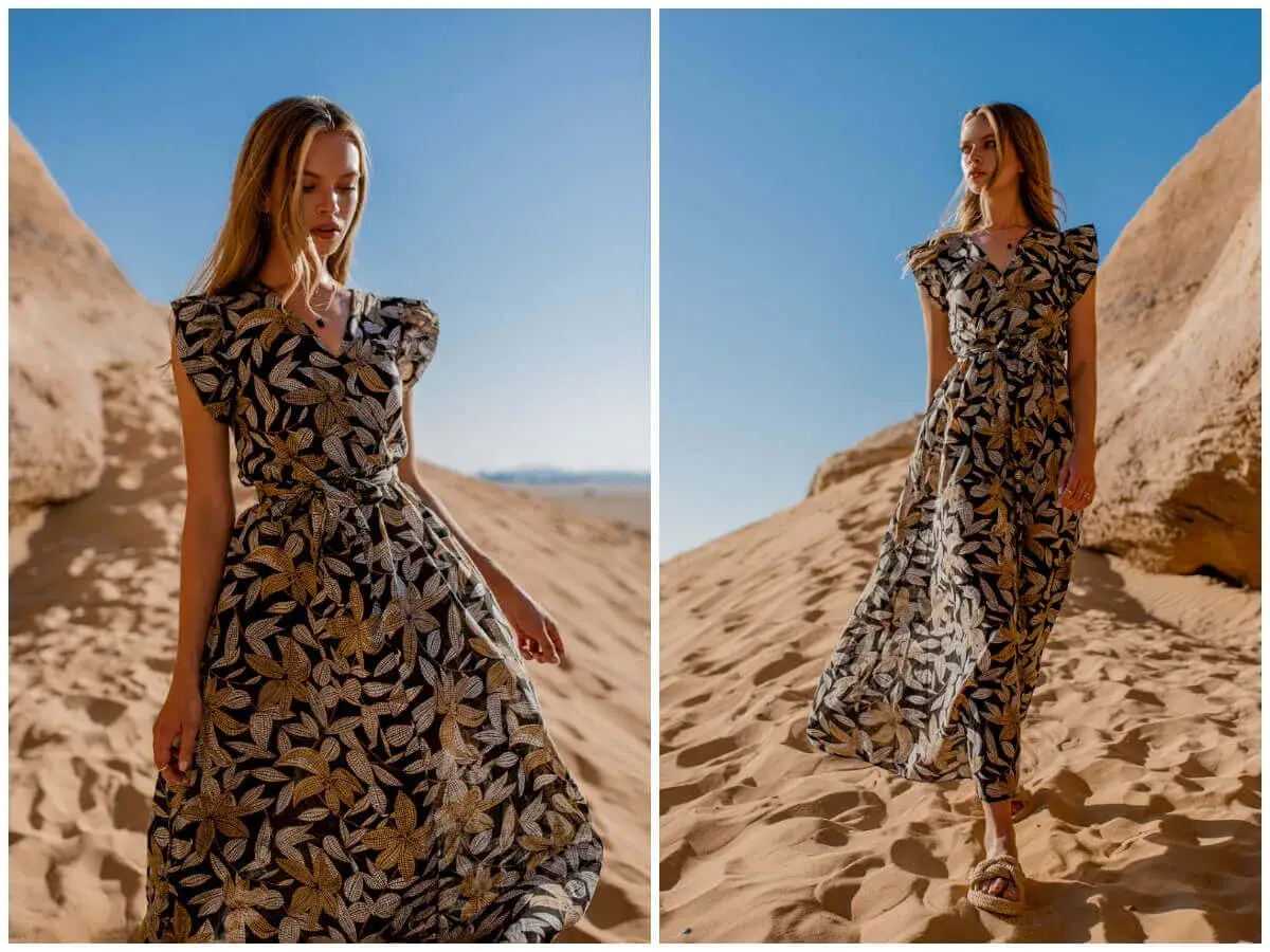 Kobieta w kwiecistej sukience empire, podkreślającej talię, pozuje na tle pustynnych wydm.