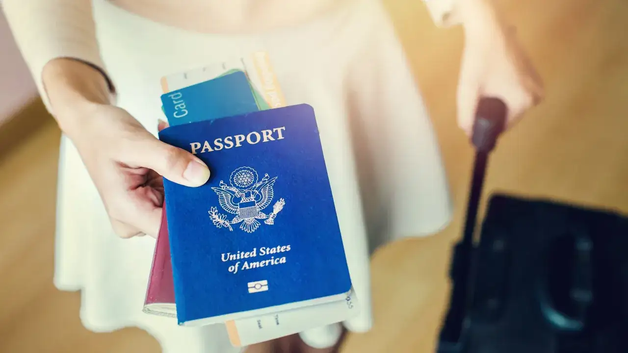 Dłoń trzyma paszport USA i karty. Czy na paszport można wziąć kredyt? Podróż marzeń czeka!