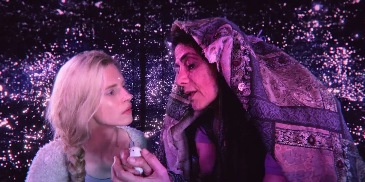 Dwie kobiety, jedna młoda, druga starsza, patrzą na siebie w otoczeniu migoczących gwiazd. To scena z serialu 