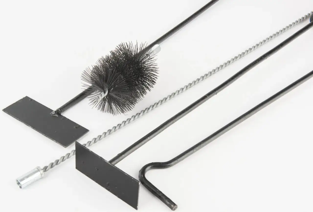 Zestaw narzędzi do czyszczenia kanałów w piecu kaflowym: szczotka, zgarniacz i drut.