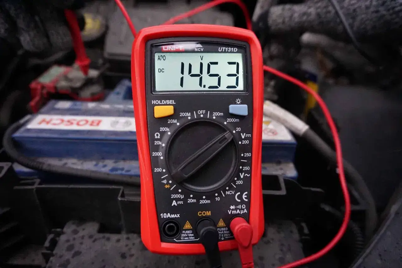 Czerwony multimetr pokazuje 14.53V, co może wskazywać na problem, gdy alternator rozładowuje akumulator.